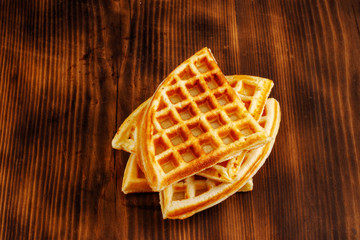 Waffles with honey, jam, and berries on wooden background