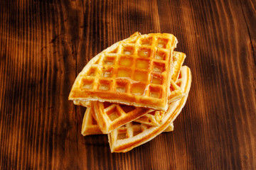 Waffles with honey, jam, and berries on wooden background