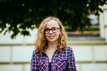 Portrait of young woman smiling with glasses against a plants background - - education, school, teamwork and people concept.