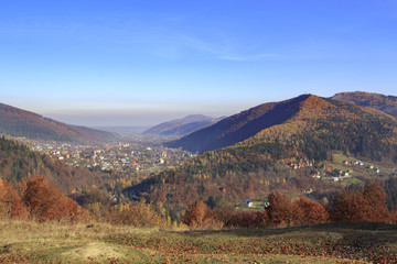 Autumn landscape in Carpathian lowlands with colorful forests and a village in a valley