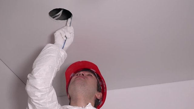 Professional worker man make drywall ceiling holes for lighting installation