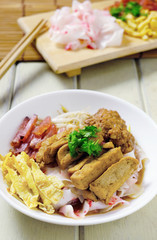 china noodle style with egg, sausage, tofu, pork ontop with gray sauce