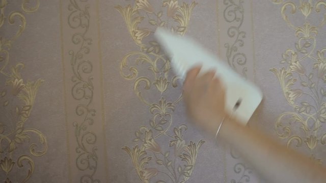 the process of gluing Wallpaper on the wall,the hand of the worker to smooth the Wallpaper with a spatula clamping.
