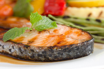 Salmon grill on teriyaki sauce and vegetable grill in white dish on the wooden table