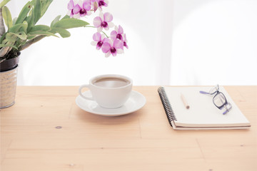 Minimal workspace,coffee cup,orchid flower ,eyeglasses and notebook on wooden table over white background ,pastel filter
