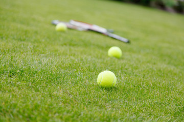 Racket and balls for tennis on green grass