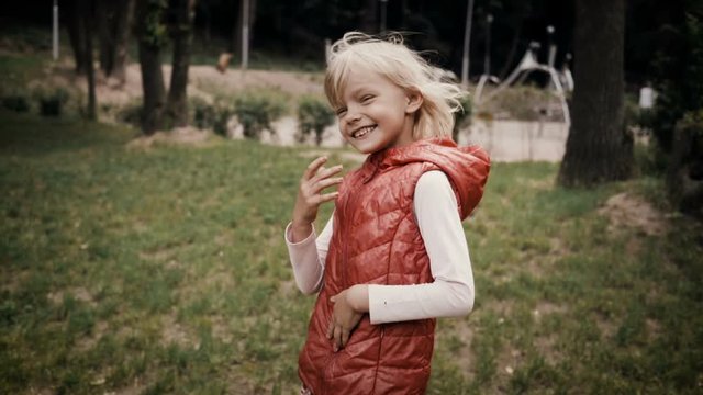 Positive emotions. Little cute blond girl smiling and happy laughing in a summer park. Slow motion. HD