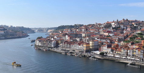 Fototapeta na wymiar Boat navigates Duoro River in View of Historic Porto, Portugal