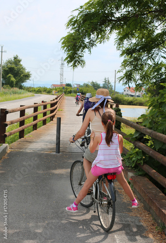 Cheerful bicycle family on the bike path in summer