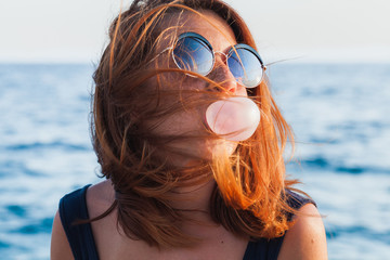 Young woman blowing bubble gum by the sea