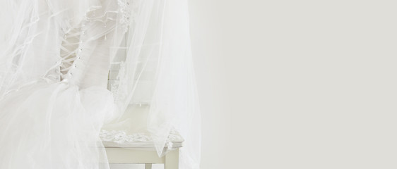 Beautiful white wedding dress and veil on chair
