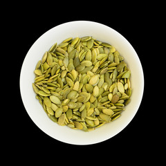 Pumpkin seeds in a bowl isolated on black