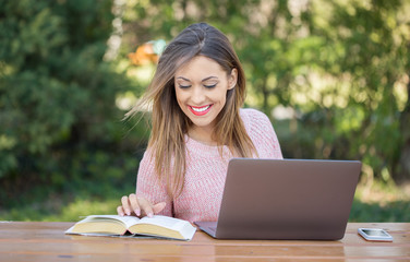 Beautiful young woman studying in a park