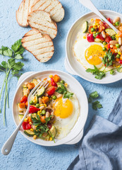 Breakfast vegetable hash with fried eggs on a blue background, top view. Healthy food concept