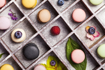 Variety of colorful french sweet dessert - les macarons with flowers and berries.