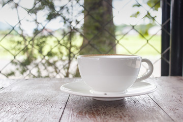 Hot white cup of coffee with heart shape on wood table with copy space.