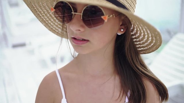 Beautiful young girl in a cap and sunglasses on the beach