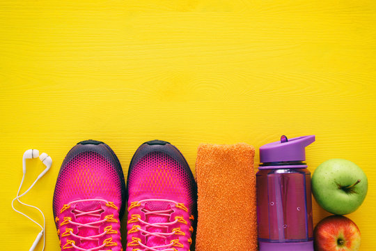 fitness concept with bottle of water, towel and woman pink sport footwear over colorful background