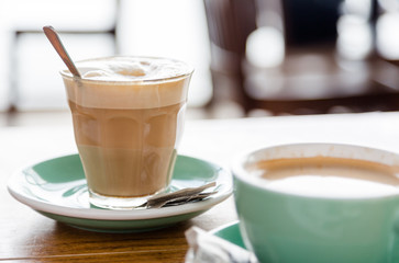 White coffee in transparentretro glass on green pot and wooden table