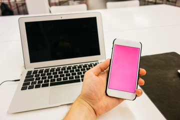 man is holding an smartphone with notebook in the background