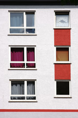 Wohnungsfenster mit bunten Gardinen  / Die Fenster eines mehrstöckigen Wohnhauses mit bunten...