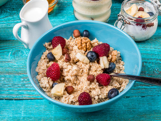 Bowl of oatmeal with raspberries and blueberries on a blue wooden table.