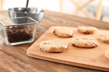 Raw dough with chocolate chips for cookies on wooden board, closeup