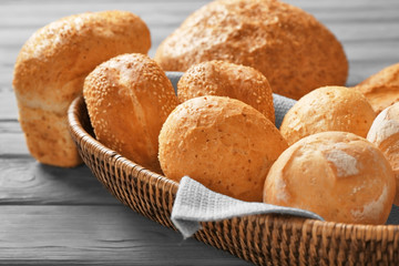 Wicker basket and delicious bread on wooden table