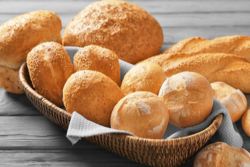 Wicker basket and delicious bread on wooden table