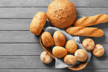 Wicker basket and delicious bread on wooden table