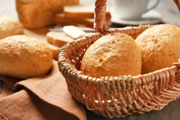 Wicker basket with delicious bread on wooden table