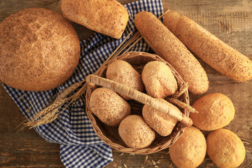 Beautiful composition with wicker basket and delicious bread on wooden table