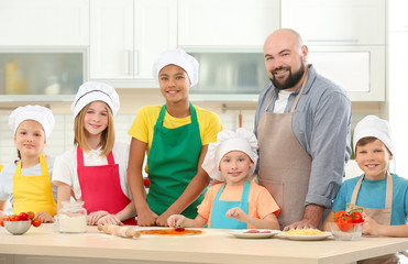 Group of children and teacher in kitchen during cooking classes