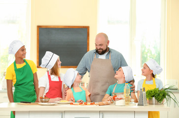 Group of children and teacher in kitchen during cooking classes