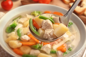 Ladle with turkey soup over plate, closeup