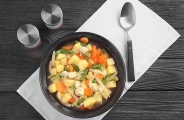 Plate with delicious turkey soup on wooden table