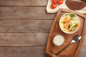 Composition with delicious turkey soup in bowl on wooden background