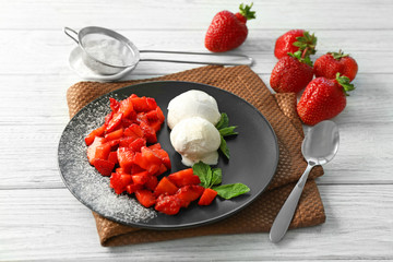 Plate with delicious sliced strawberry, mint leaves and ice-cream on wooden table