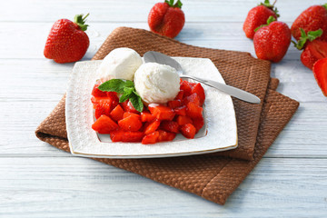 Plate with delicious strawberry and ice-cream on wooden table