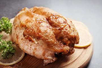 Cutting board with delicious cooked turkey fillet on table, closeup