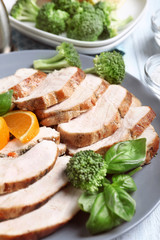 Plate with delicious sliced turkey fillet and orange on table, closeup