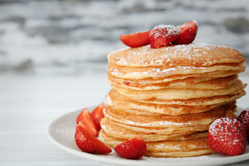 Plate with delicious pancakes on blurred background