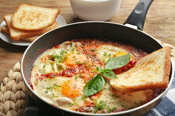 Frying pan with eggs in purgatory on table