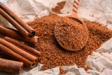 Cinnamon sugar in wooden spoon on paper, closeup