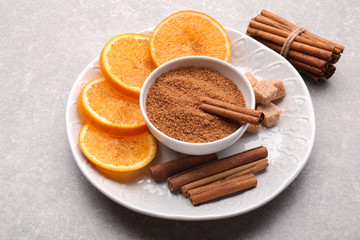 Composition with cinnamon sugar and orange slices on grey background