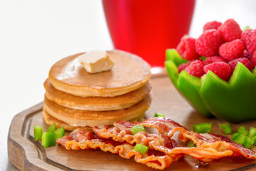 Tasty breakfast with pancakes, bacon and raspberry on wooden board