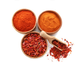 Three wooden bowls with chili powder, flakes and seeds isolated on white