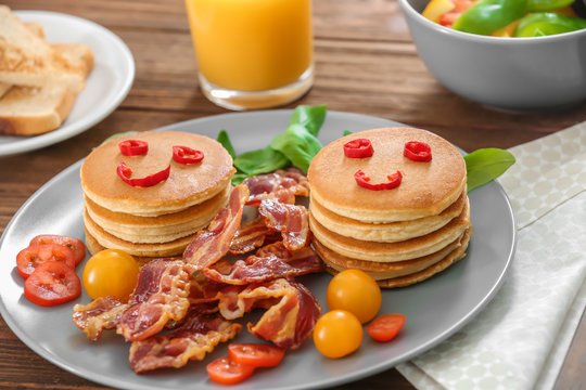 Creative tasty breakfast with pancakes and bacon on table