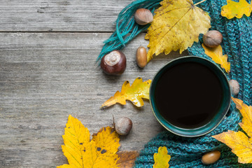 Autumn background with dry leaves, scarf and hot cup of coffee on wooden table