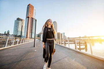 Foto op Plexiglas Lifestyle portrait of a young stylish businesswoman walking the bridge during the morning in Rotterdam © rh2010